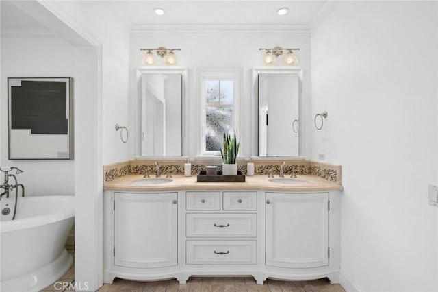 bathroom with double vanity, a freestanding bath, ornamental molding, and a sink