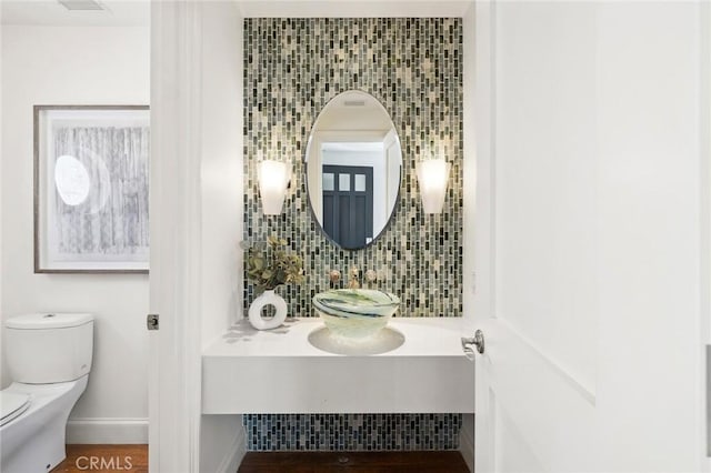 bathroom with visible vents, tasteful backsplash, toilet, and baseboards