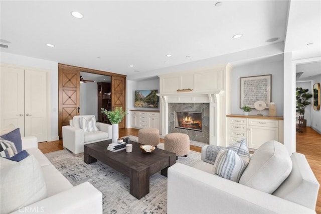 living area featuring light wood finished floors, a premium fireplace, and recessed lighting