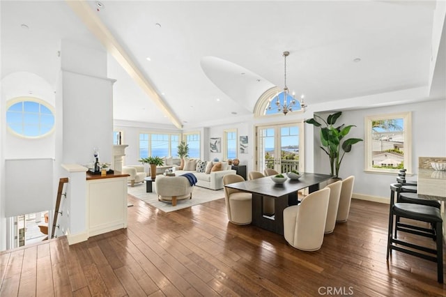 dining room featuring dark wood-type flooring, a chandelier, a healthy amount of sunlight, and vaulted ceiling