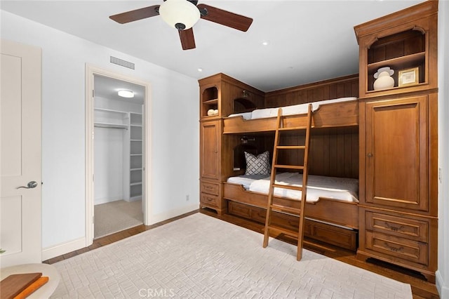 bedroom featuring baseboards, visible vents, wood finished floors, a spacious closet, and a closet