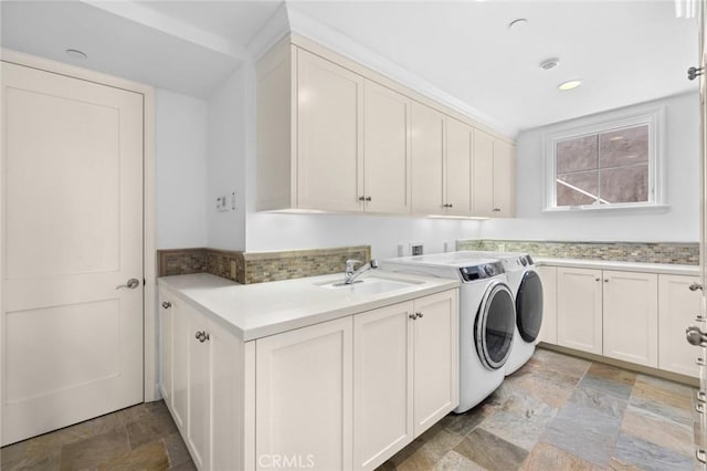 laundry area featuring recessed lighting, a sink, cabinet space, stone finish flooring, and washer and clothes dryer