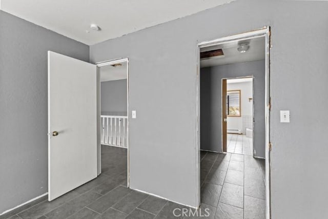 unfurnished bedroom featuring dark tile patterned flooring, a closet, and a baseboard radiator