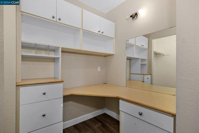 unfurnished office featuring dark hardwood / wood-style floors and built in desk