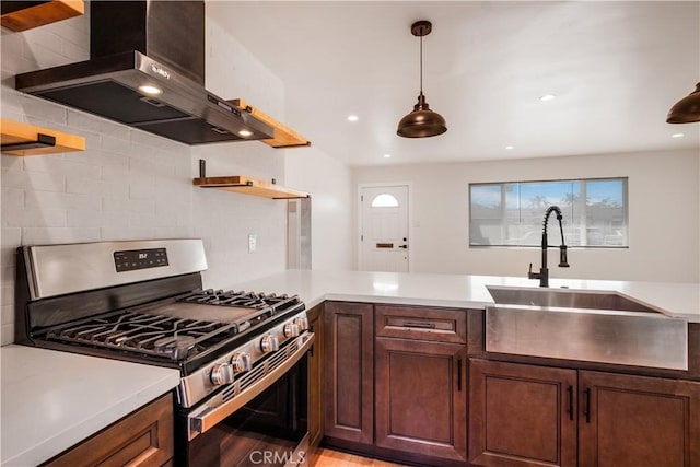 kitchen with decorative backsplash, stainless steel range with gas stovetop, wall chimney range hood, open shelves, and a sink