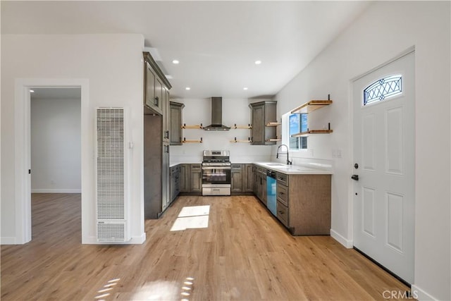 kitchen with open shelves, light wood-style flooring, appliances with stainless steel finishes, a sink, and wall chimney exhaust hood