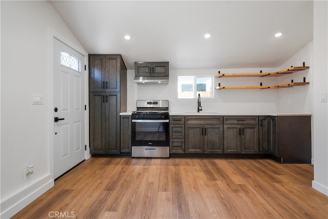 kitchen with stainless steel range with gas stovetop, light hardwood / wood-style flooring, dark brown cabinets, and sink