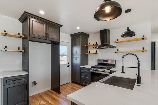 kitchen with wall chimney exhaust hood, backsplash, stainless steel gas range, open shelves, and a sink