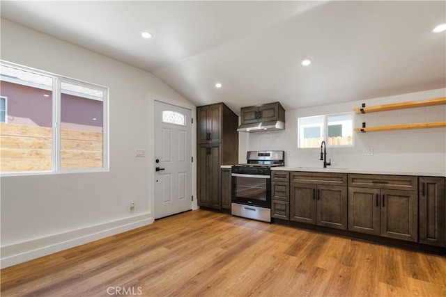 kitchen with light countertops, light wood-type flooring, under cabinet range hood, a sink, and gas stove