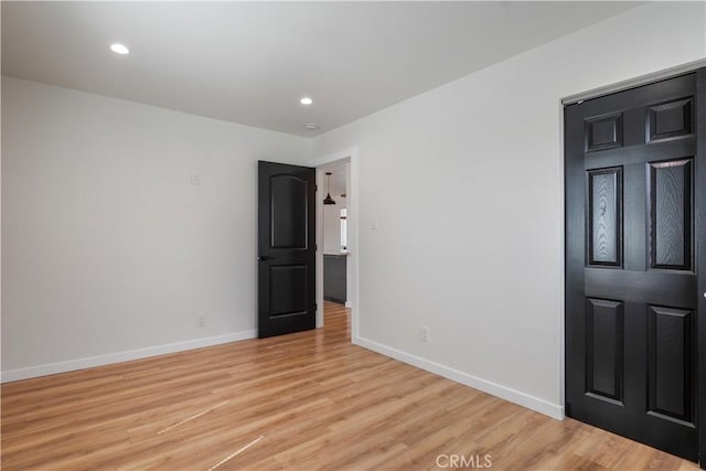 spare room featuring light wood finished floors, baseboards, and recessed lighting