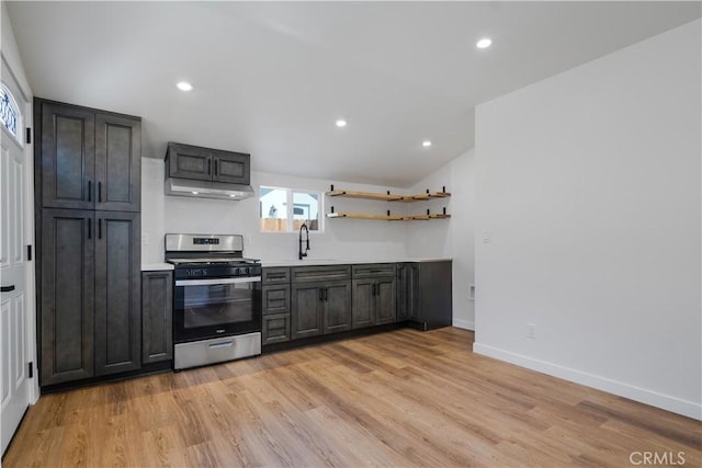 kitchen featuring stainless steel gas range oven, light wood-style flooring, under cabinet range hood, a sink, and light countertops