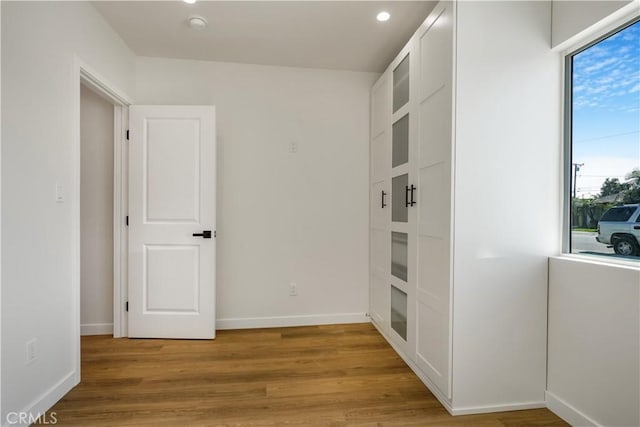 hall with light wood-style floors and baseboards