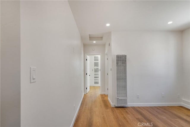 corridor with light wood-style floors, recessed lighting, a heating unit, and baseboards