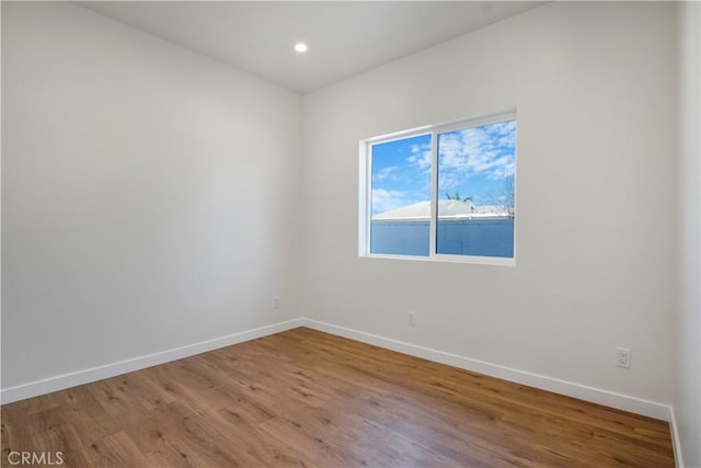 spare room with recessed lighting, wood finished floors, and baseboards