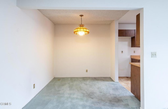 unfurnished dining area with light colored carpet and a textured ceiling