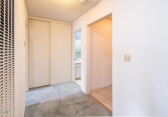 corridor with light carpet and a textured ceiling