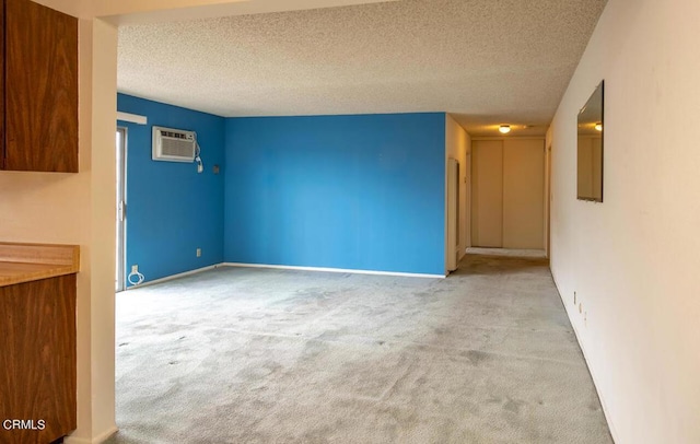 unfurnished living room featuring a wall mounted air conditioner, light colored carpet, and a textured ceiling