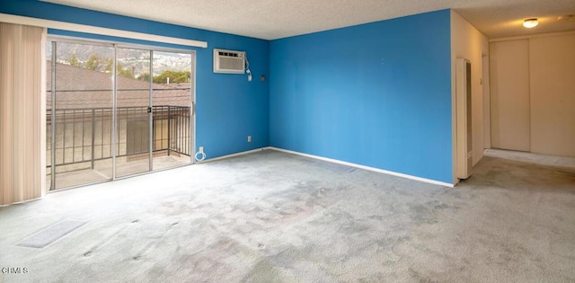 carpeted empty room with an AC wall unit and a textured ceiling