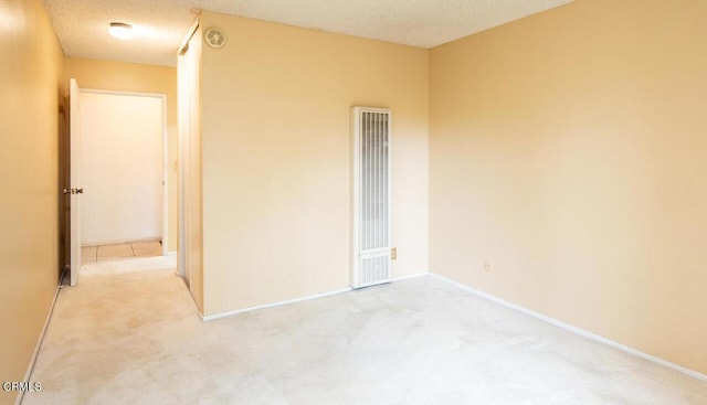 spare room featuring a textured ceiling and light carpet