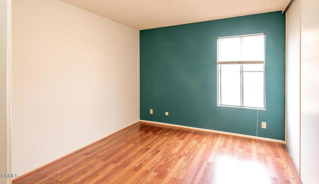 empty room with light hardwood / wood-style floors and a textured ceiling