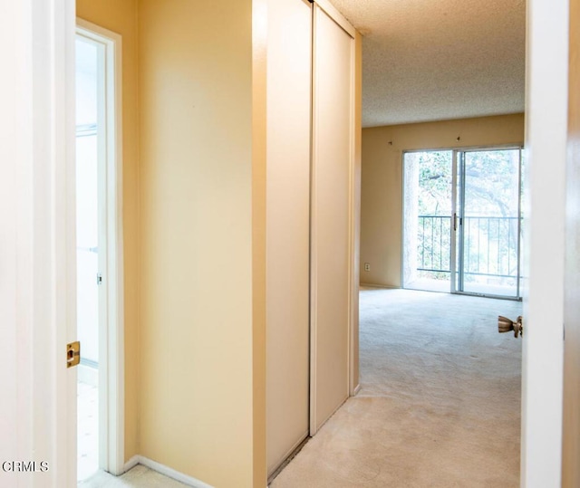 corridor featuring light colored carpet and a textured ceiling