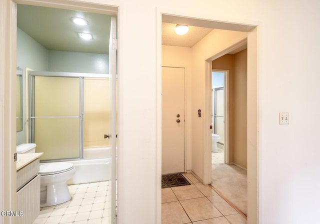 full bathroom with combined bath / shower with glass door, vanity, and toilet