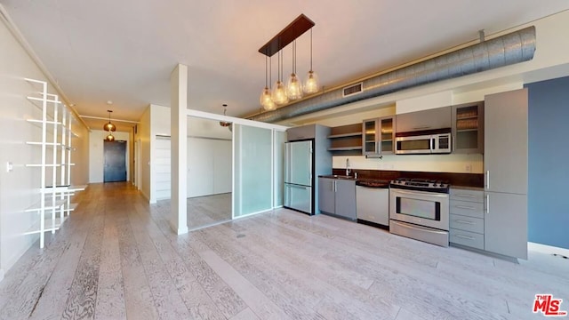 kitchen with sink, stainless steel appliances, decorative light fixtures, and light wood-type flooring