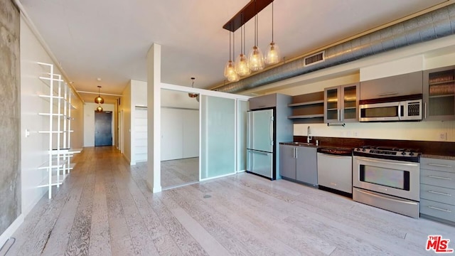 kitchen featuring light hardwood / wood-style flooring, stainless steel appliances, decorative light fixtures, and sink