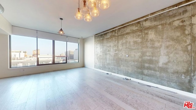 unfurnished room with wood-type flooring and a notable chandelier