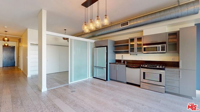 kitchen featuring decorative light fixtures, stainless steel appliances, light hardwood / wood-style flooring, and sink