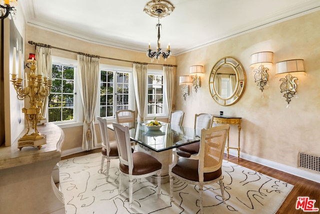 dining space with ornamental molding, a chandelier, and light wood-type flooring