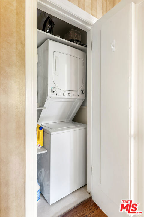 laundry area with hardwood / wood-style floors and stacked washer and dryer