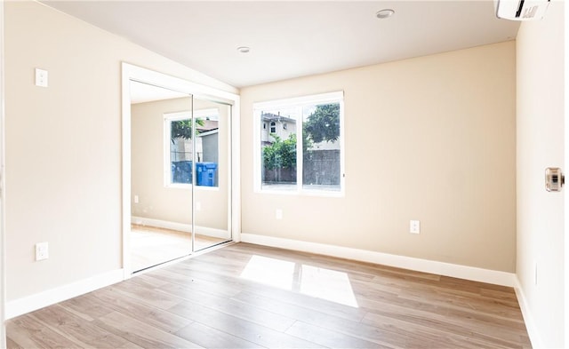 unfurnished bedroom with a closet, vaulted ceiling, and light hardwood / wood-style flooring