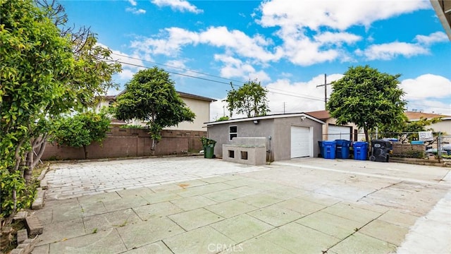 view of patio with a garage and an outbuilding