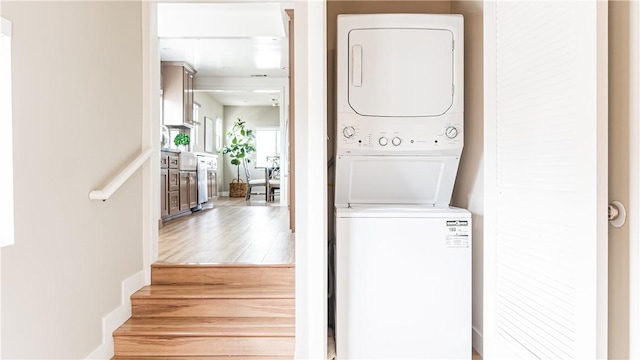 laundry area featuring hardwood / wood-style flooring and stacked washer / drying machine