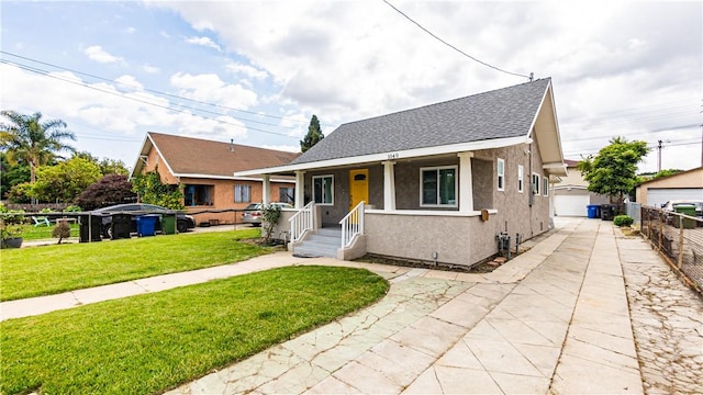 bungalow-style house featuring a porch, a garage, an outbuilding, and a front lawn