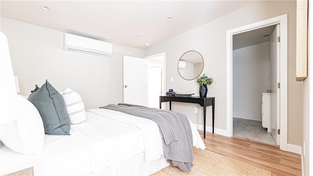 bedroom with a wall mounted air conditioner and light hardwood / wood-style floors