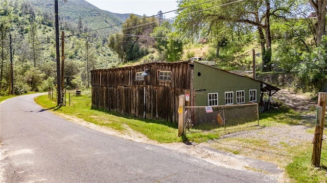 view of property exterior with a mountain view, a forest view, and fence