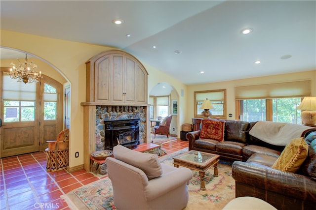 tiled living room with a healthy amount of sunlight, lofted ceiling, a chandelier, and a fireplace