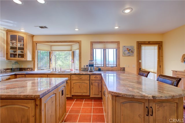 kitchen with light stone countertops, sink, a kitchen island, and a kitchen breakfast bar