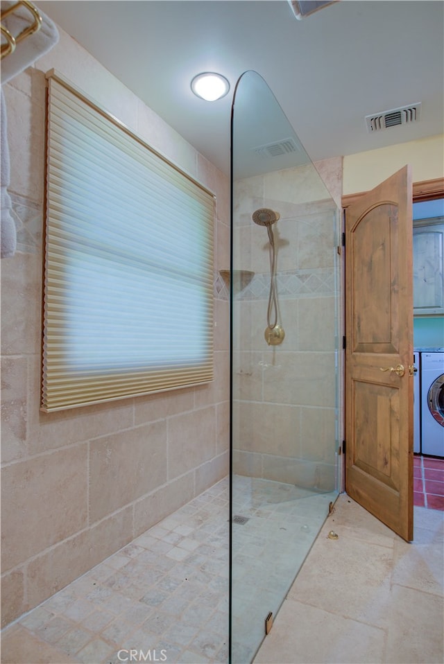 bathroom featuring washer / dryer and a tile shower