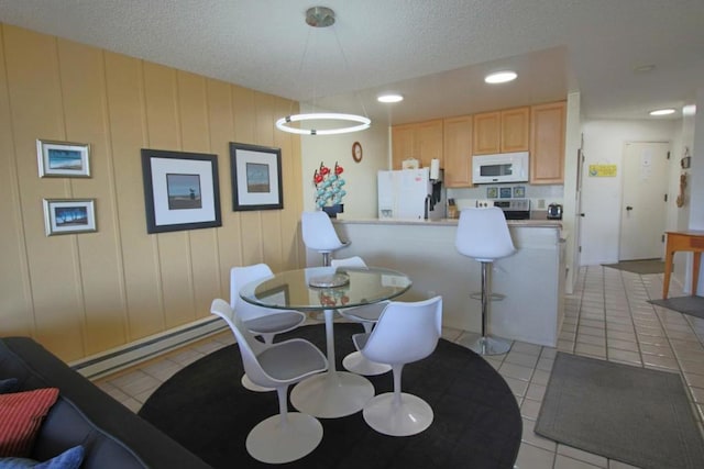 dining space featuring a textured ceiling, baseboard heating, and light tile patterned flooring