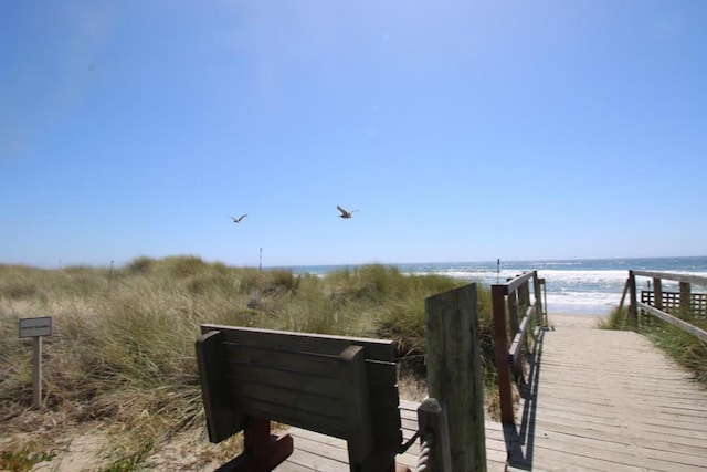 view of dock featuring a water view and a view of the beach