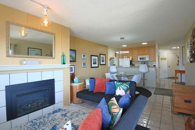 living room featuring a textured ceiling, light tile patterned flooring, and a fireplace