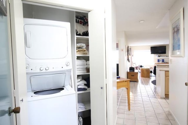 clothes washing area with stacked washer / dryer and light tile patterned floors