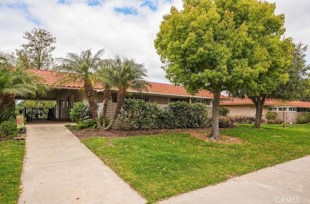 mediterranean / spanish-style home featuring a front lawn and a carport