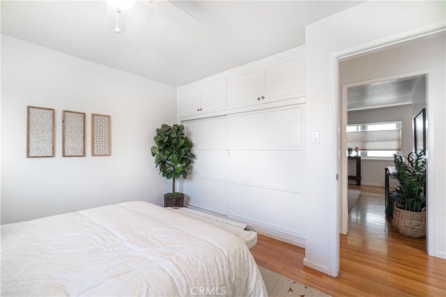 bedroom with ceiling fan, light wood-type flooring, and a closet