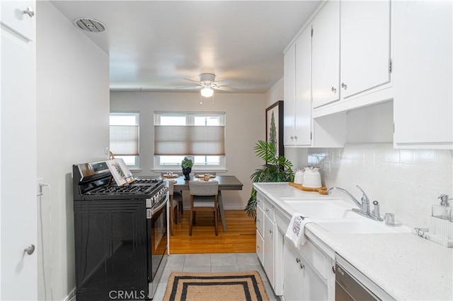 kitchen with white cabinets, ceiling fan, gas stove, and sink