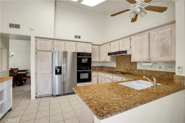 kitchen with sink, appliances with stainless steel finishes, a high ceiling, light stone countertops, and kitchen peninsula