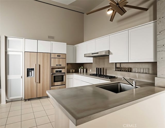 kitchen with white cabinetry, sink, stainless steel appliances, and kitchen peninsula